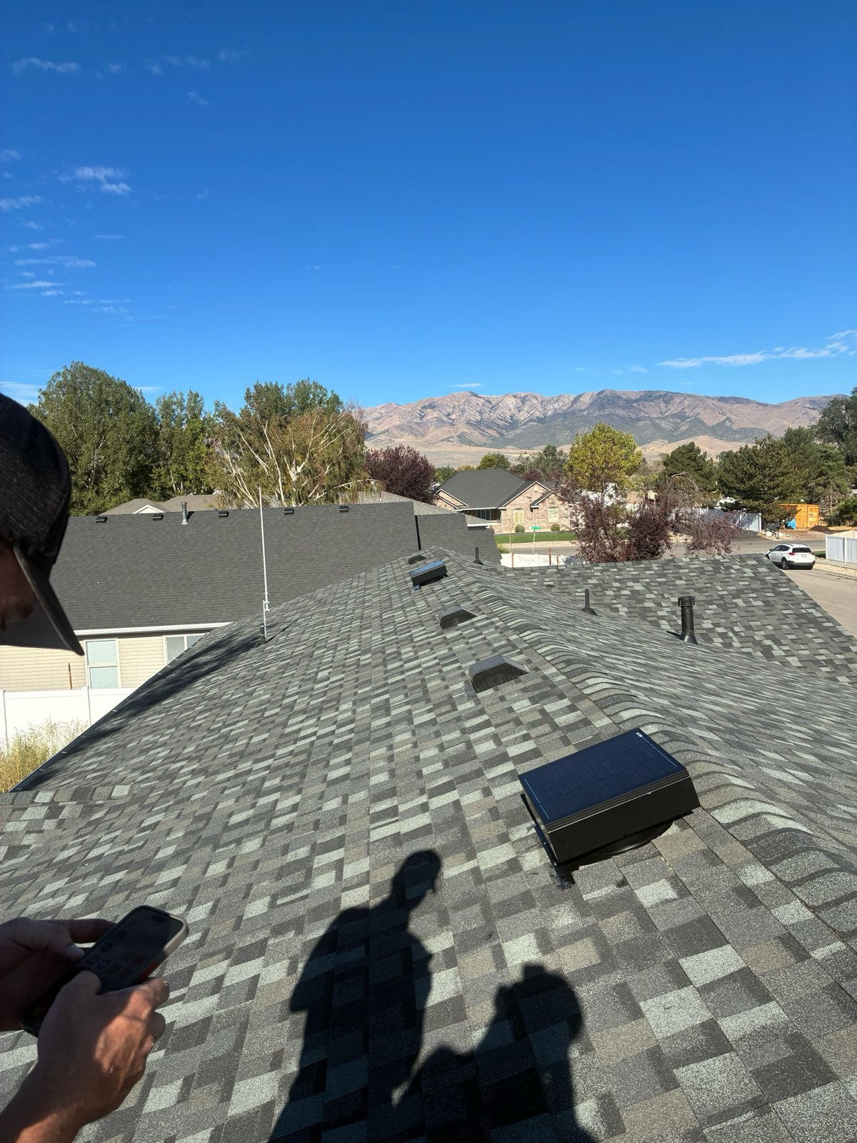 View from the roof ridge over a finished solar attic fan install, with mountains in the distance.