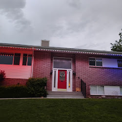 Brick home lit in red, white and blue permanent lighting