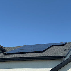 Solar panel array on a shingle roof against a clear blue sky